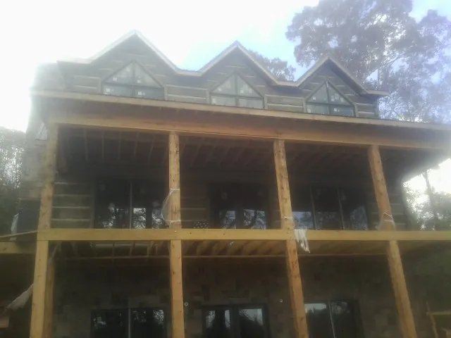 Dormers and porch framing on a large log home under construction — Roof Coating work by our crew in Litchfield