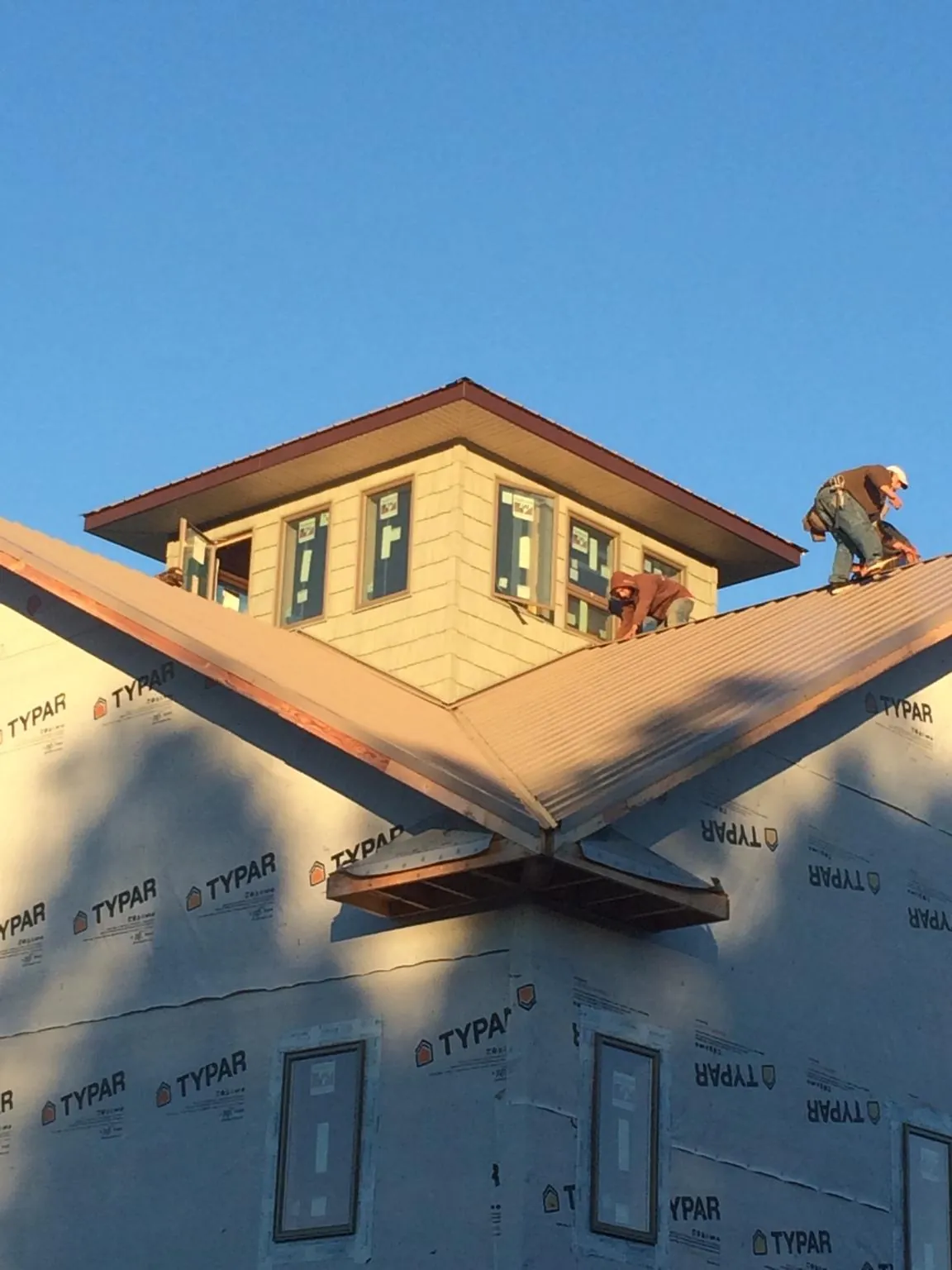 Roofers working around a rooftop cupola on a new metal roof at sunset — Roof Waterproofing in Litchfield by Roofing Brothers